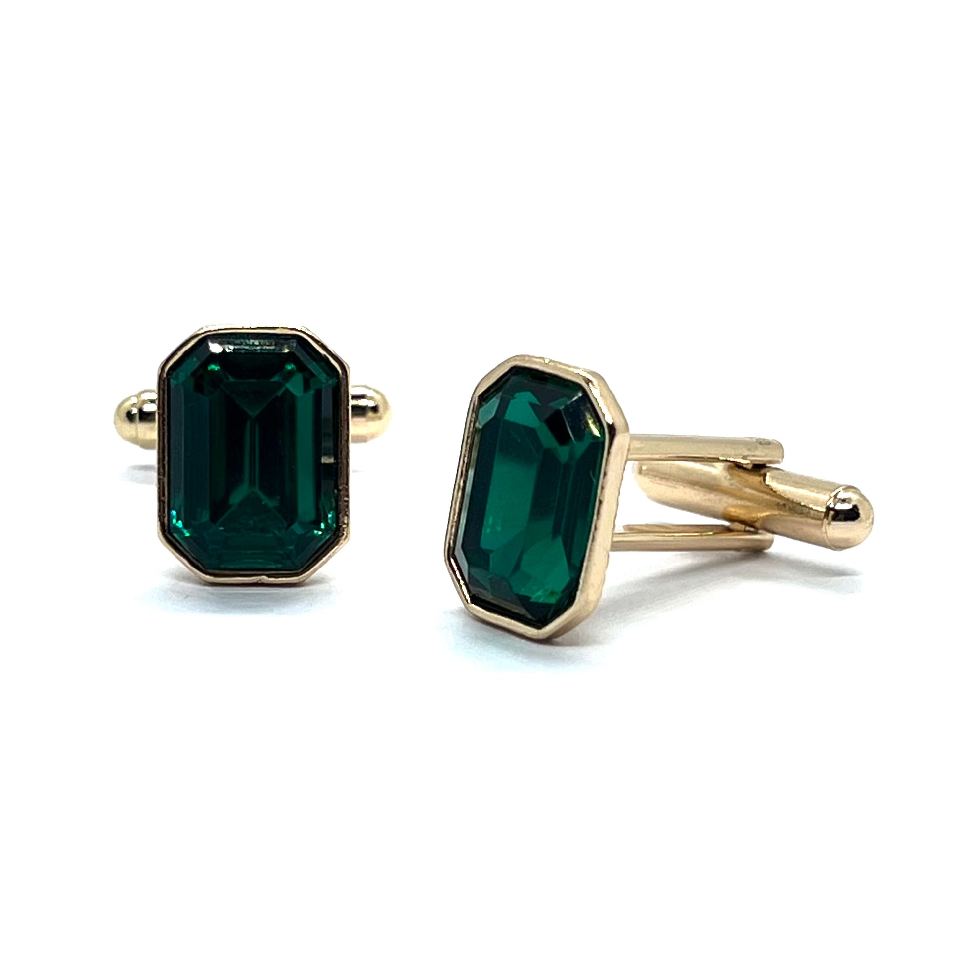 A pair of golden cufflinks with rectangular emerald green gemstones set in gold-colored metal.