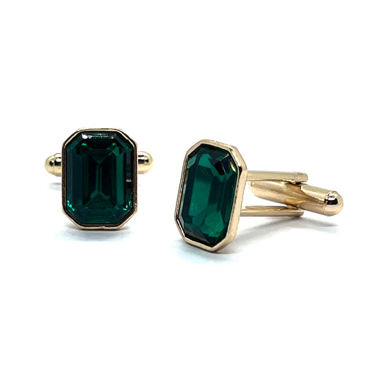 A pair of golden cufflinks with rectangular emerald green gemstones set in gold-colored metal.